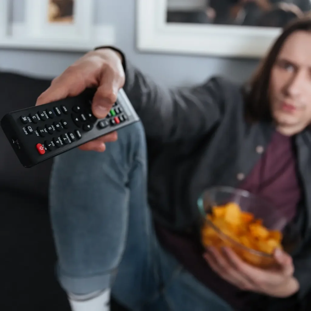Televisor tarda en encender. Imagen de un usuario apretando los botones de un mando a distancia sin éxito.